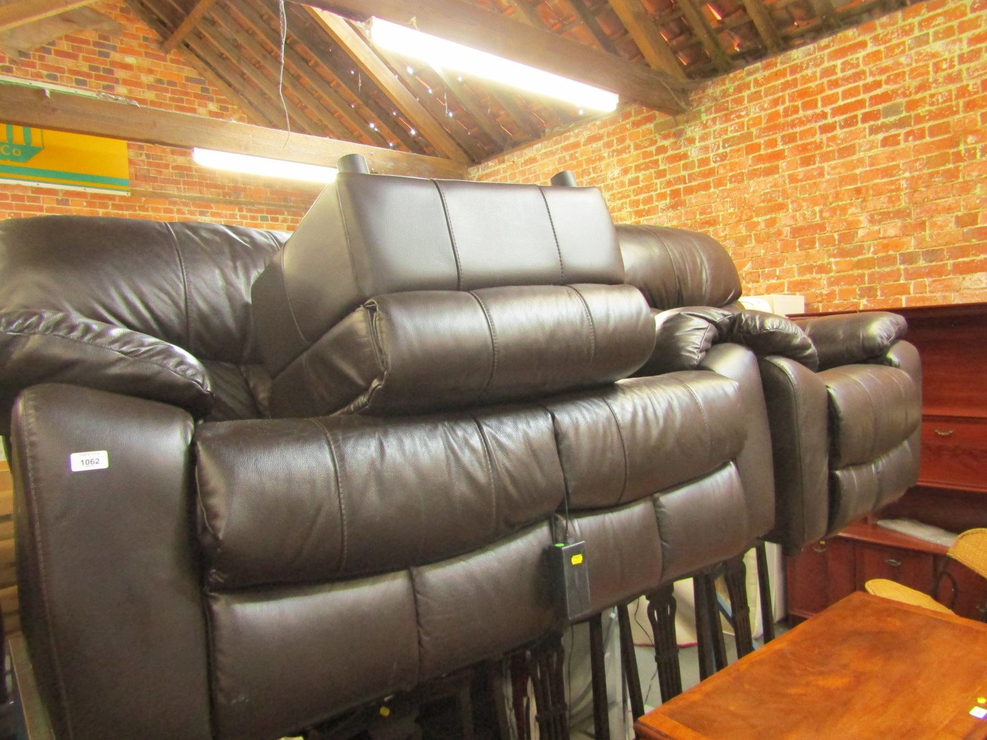 A black sofa suite, comprising a two seater reclining sofa, an armchair, and a footstool. (3)