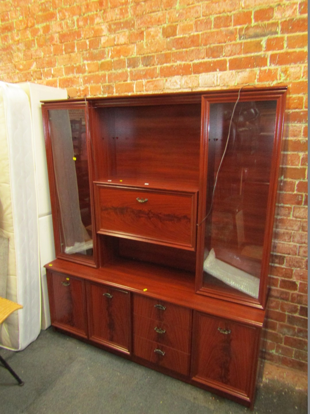 A mahogany display unit with a drinks cabinet, flanked by glazed .