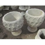A pair of reconstituted stone pineapple planters, with shaped sides on a circular foot, 50cm high,