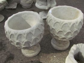 A pair of reconstituted stone pineapple planters, with shaped sides on a circular foot, 50cm high,