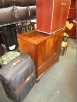 A suitcase, reproduction television cabinet, and a mahogany finish two door cupboard. (3)
