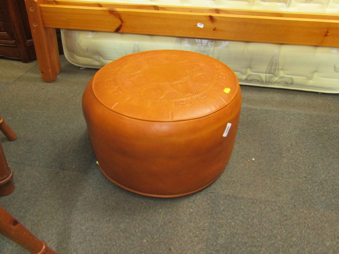 A tan leather footstool, with an embossed design. The upholstery in this lot does not comply with