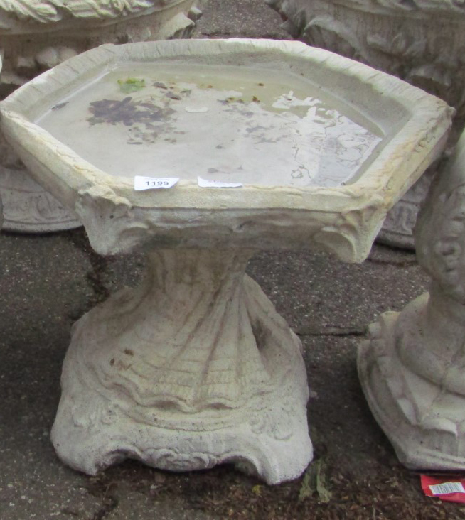 A reconstituted stone low bird table, on a conch shell base, 37cm high, 45cm wide.