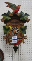 A cuckoo clock, in beech casing with applied green maple leaves and birds, with weights.