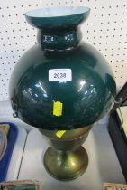 An oil lamp, with a dark green shade, chimney on a brass base.