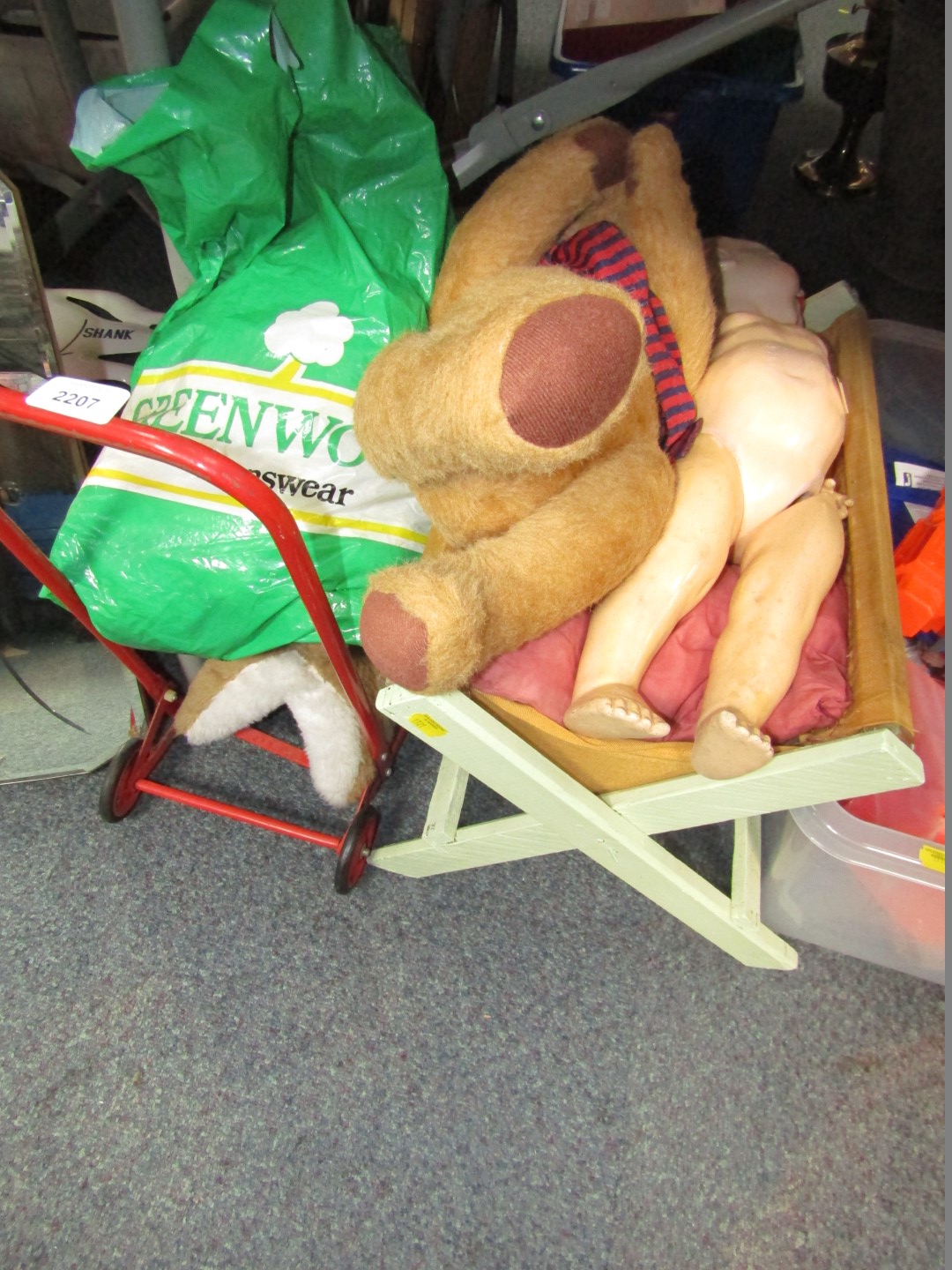 A push along dog, various doll's clothing, a doll and crib, and a plush jointed Teddy bear.