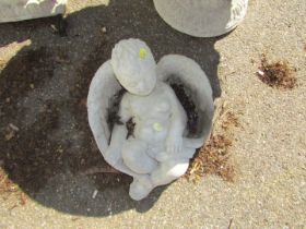 A reconstituted stone figure of a child sleeping in wings, 30cm wide.