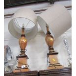 A pair of turned table lamps, each baluster form, on a square foot, with taupe shades.