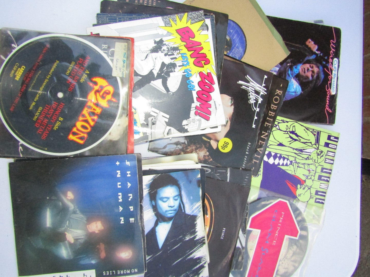 A group of vinyl singles, including Saxon, Cliff Richard, Prince and the Revolution, Girls & Boys,