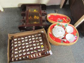 A mahogany display case, with small group of Teddies, a group of thimbles, and a wicker basket