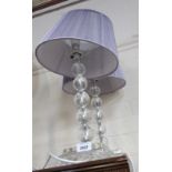 A pair of crystal style table lamps, with purple shades.