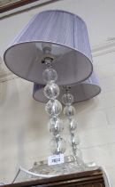 A pair of crystal style table lamps, with purple shades.