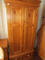 A pine double wardrobe, with moulded cornice, on drawer base.