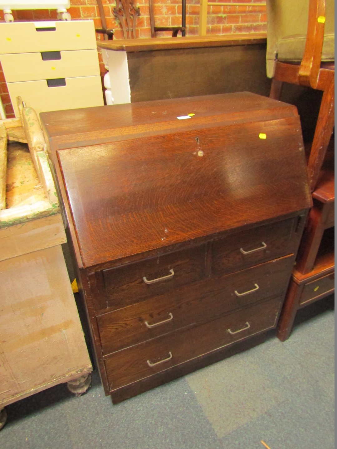 A 20thC oak bureau, with fall flap above an arrangement of two short and two long drawers, with