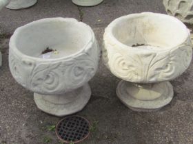 A pair of reconstituted stone garden urns, each of scroll and feather design, on a circular foot,