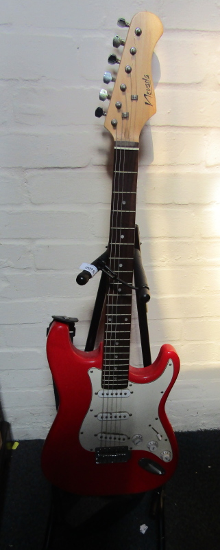 A red electric guitar, with Nevada decal, on stand.