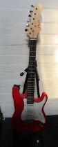 A red electric guitar, with Nevada decal, on stand.