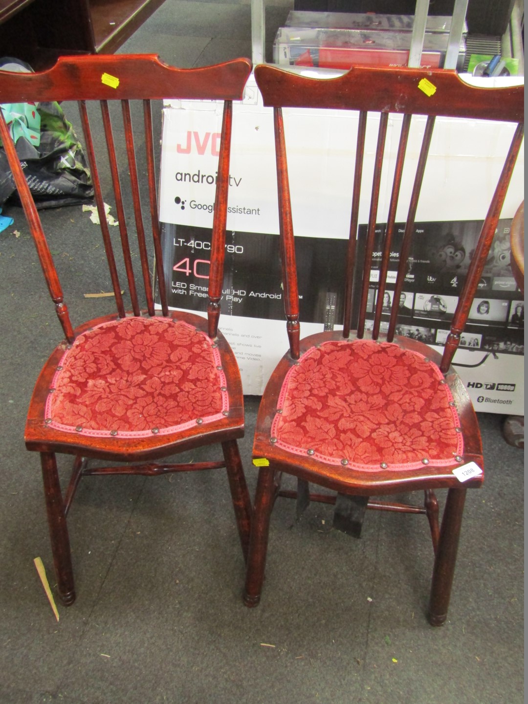 A pair of stained oak bedroom chairs, each with a red floral patterned overstuffed seat.