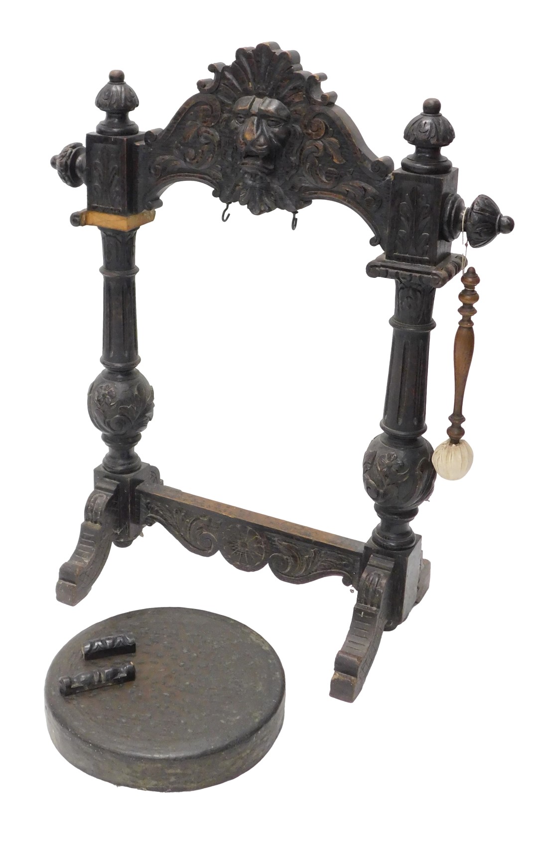 A Victorian ebonised oak dinner gong, the frame with a central lion mask, carved overall with leaves