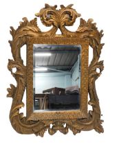 A gilt gesso rococo scroll wall mirror, with an oval plate.