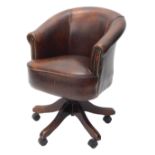 A brown leather and brass studded office chair, on X shaped base, with castors. The upholstery in t