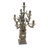 A modern bronze effect nine branch candelabra, the base formed as an urn with dolphins, on a stepped