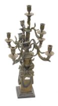 A modern bronze effect nine branch candelabra, the base formed as an urn with dolphins, on a stepped