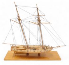 A wooden scale model of a two masted sailing ship, on a rectangular base, 64cm long.