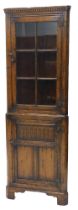 A Titchmarsh and Goodwin oak standing corner cabinet, the glazed door with iron butterfly shaped hin