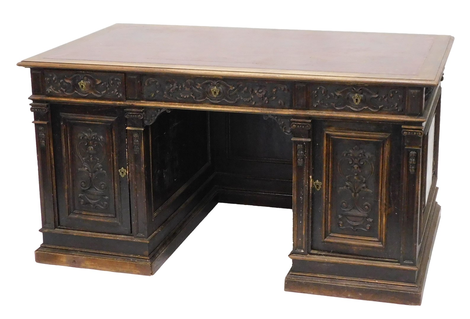 A Continental carved oak pedestal desk, the rectangular top with an ox blood red leatherette inset,