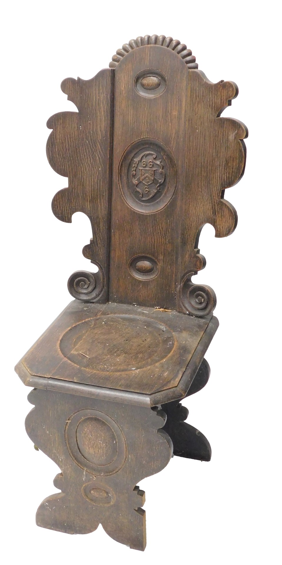 A Continental oak hall chair, the back with shaped sides carved centrally with a crest, with a solid