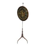 A 19thC mahogany pole screen, the oval banner embroidered in silk with leaves, berries surrounding a
