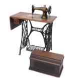 A Singer cast iron treadle sewing machine, with a walnut veneer table base and cast iron end support