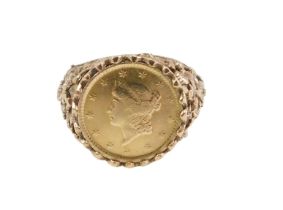 An American one dollar dress ring, the coin in a rub over mount with floral design shoulders dated 1