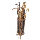 A quantity of walking sticks, shooting sticks, golf club, etc., in stand with turned supports.