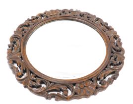 An oak wall mirror, with a foliate scroll carved border and a circular bevelled plate, 65cm diameter