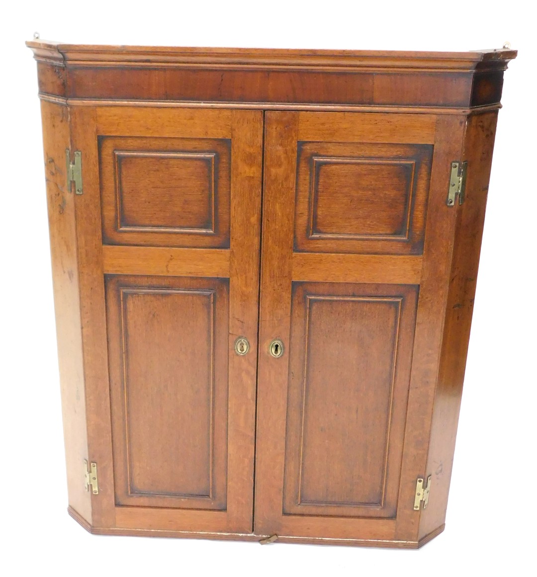 A 19thC oak and mahogany cross banded corner cabinet, with moulded cornice above two panelled doors,