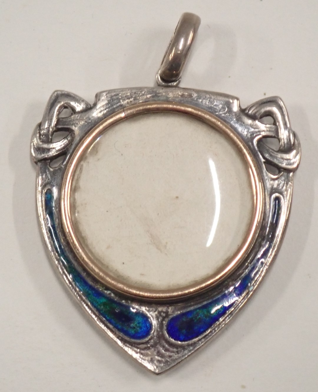 An Art Nouveau shield locket, with a brushed gold central section, in a white metal case set with bl - Image 2 of 2