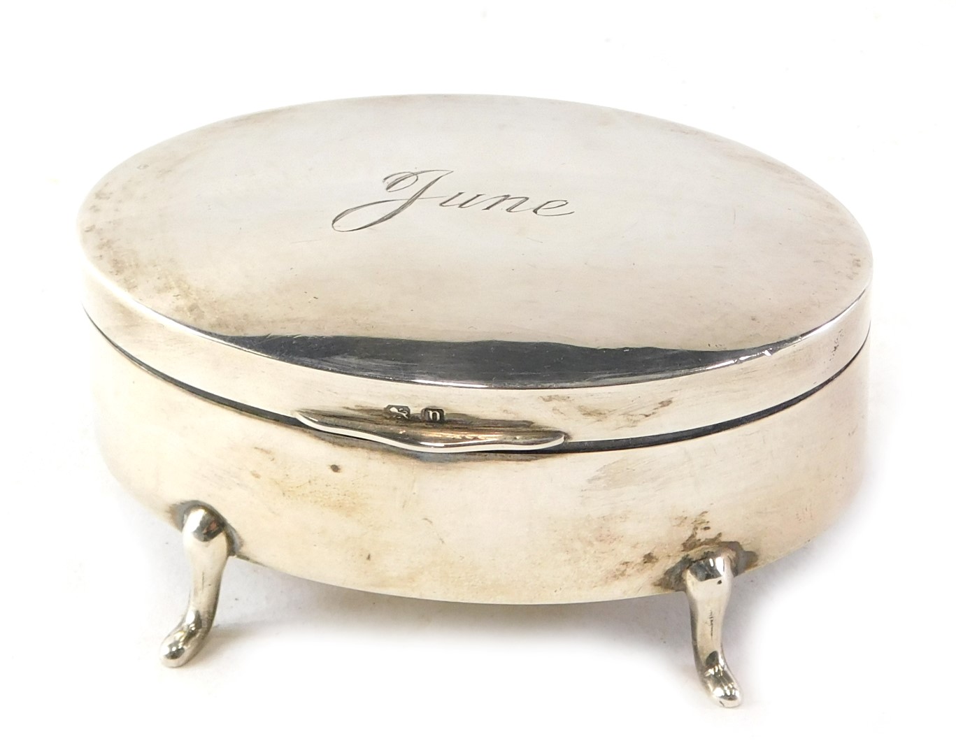 A George V oval silver jewellery box, of plain design, with hinged lid, engraved 'June', on four fee