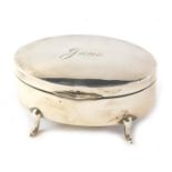 A George V oval silver jewellery box, of plain design, with hinged lid, engraved 'June', on four fee
