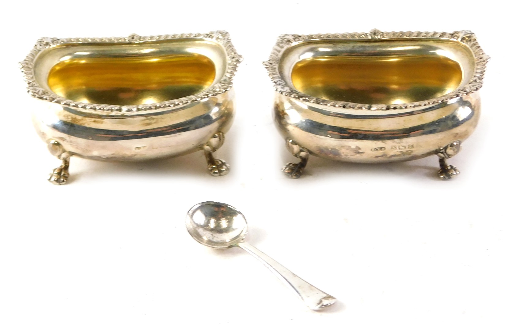 A pair of Edwardian silver salts, of swollen oblong form, with gadrooned and shell borders on claw f