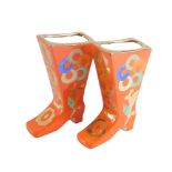 A pair of Russian porcelain boots, each painted on an orange ground marked Mockba, with numbers and
