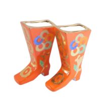 A pair of Russian porcelain boots, each painted on an orange ground marked Mockba, with numbers and