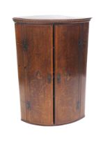 A 19thC oak and mahogany crossbanded bow fronted corner cabinet, with a chequer banded frieze, the t