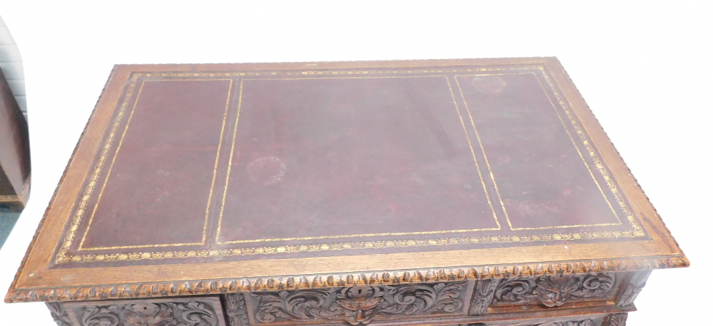 A late Victorian oak pedestal desk, carved with scrolls, leaves and masks, the rectangular top with - Image 2 of 3