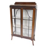 An early 20thC mahogany display cabinet, with a raised back, two glazed doors on splayed legs, 131cm