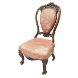 A Victorian mahogany nursing chair, the shield shaped back carved with leaves and flowers, with a pa