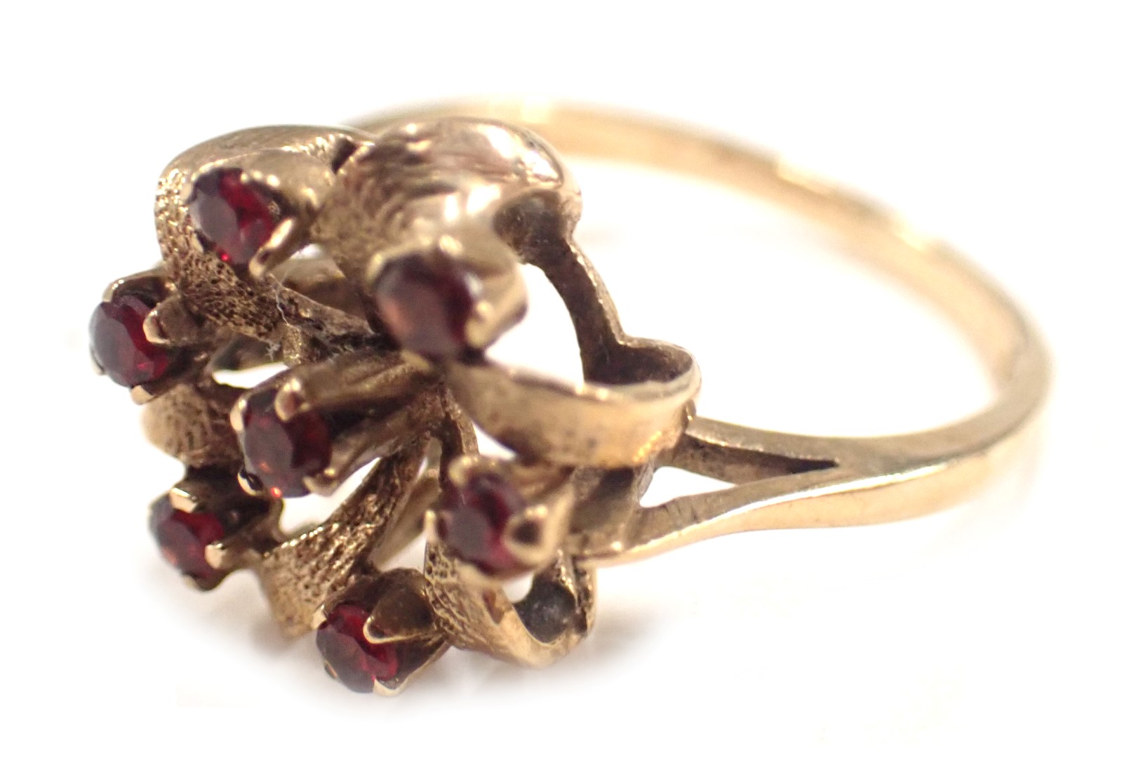 A 9ct gold cluster ring, the twist cluster set with arrangement of seven garnets, each in claw setti