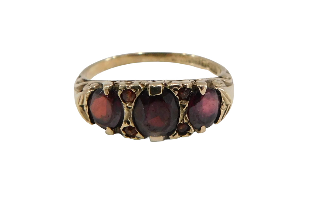 A 9ct gold garnet dress ring, set with three oval garnets and four round brilliant cut garnets, in g