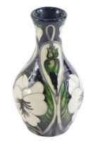 A Moorcroft squat vase, on a black ground with white painted flower decoration, numbered and signed
